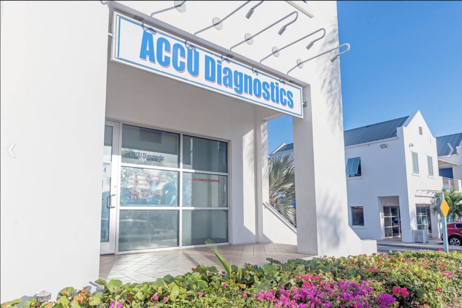 AccuDiagnostics building exterior in Providenciales — bright facade with the AccuDiagnostics signage, palm trees and bougainvillea.